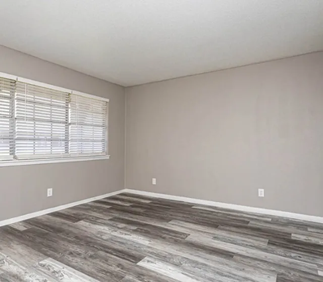 Bright and spacious room featuring modern wood flooring and large windows for ample natural light.