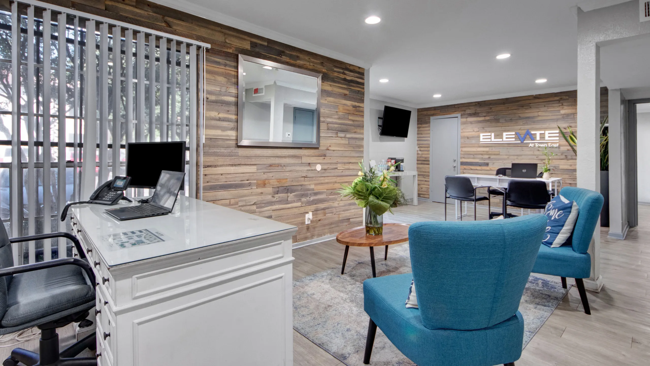 Modern office lobby with stylish blue chairs, sleek wooden accents, and a welcoming atmosphere.
