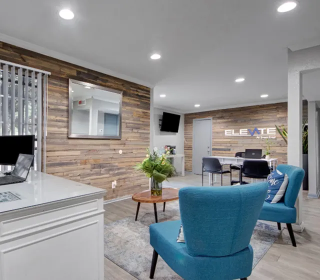 Chic modern office space with vibrant blue chairs, wood-accented walls, and inviting natural light, creating an elegant and welcoming atmosphere.