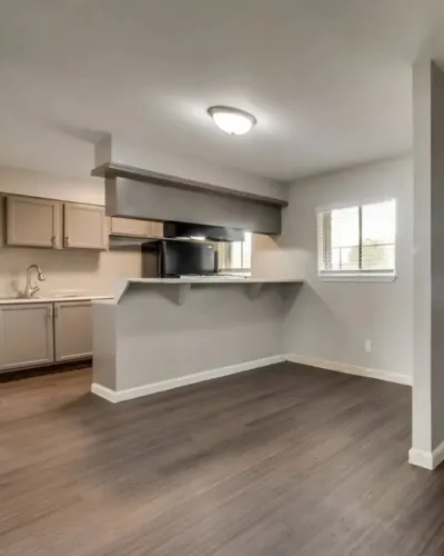 Modern kitchen with sleek cabinetry and open layout, featuring dark hardwood floors and abundant natural light.
