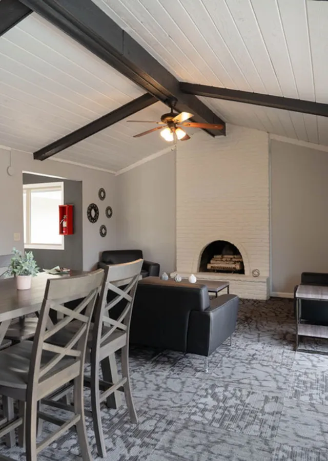 Charming living space with vaulted ceiling beams, cozy brick fireplace, and modern decor.