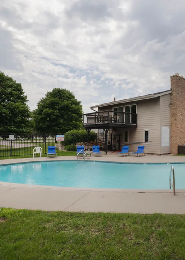 Inviting apartment complex with a sparkling pool, surrounded by lush greenery and modern architecture, perfect for relaxation and leisure.