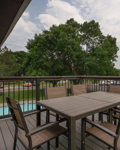 Inviting balcony with elegant outdoor dining set overlooking lush green trees, offering an ideal spot for relaxation and entertaining.