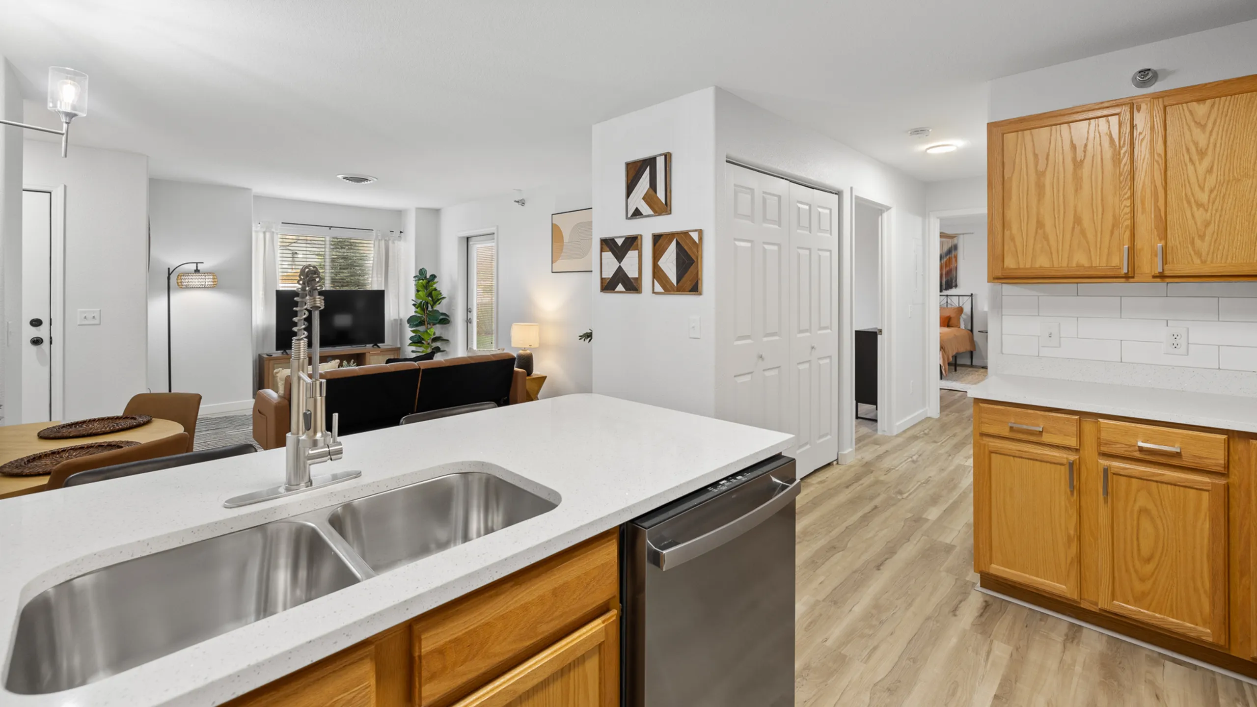 Bright and modern apartment interior featuring an open-concept layout with a sleek kitchen, cozy living room, and inviting dining area. Warm wooden cabinets and stylish decor create a welcoming atmosphere.