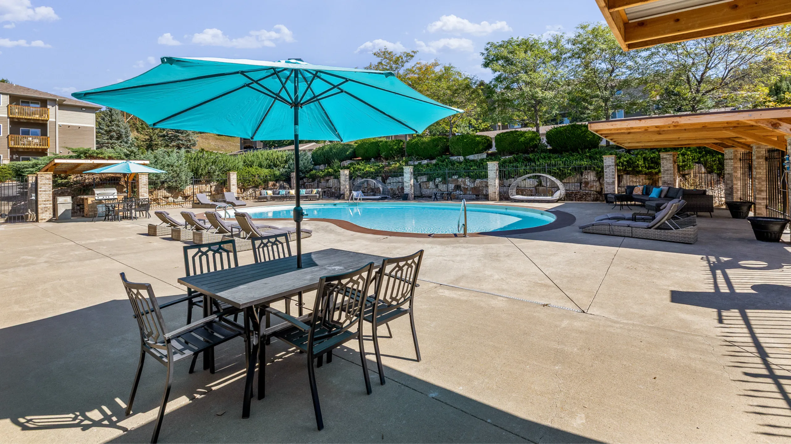 Inviting outdoor pool area with lounge chairs, shaded seating, and lush greenery, perfect for relaxation and leisure.