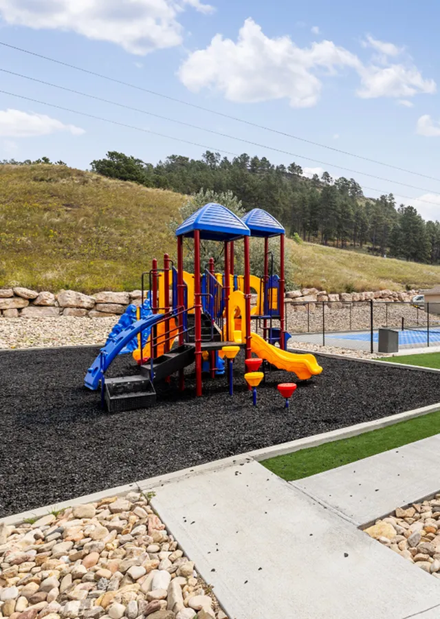 Charming playground with vibrant slides and climbing structures set against a scenic, natural landscape.