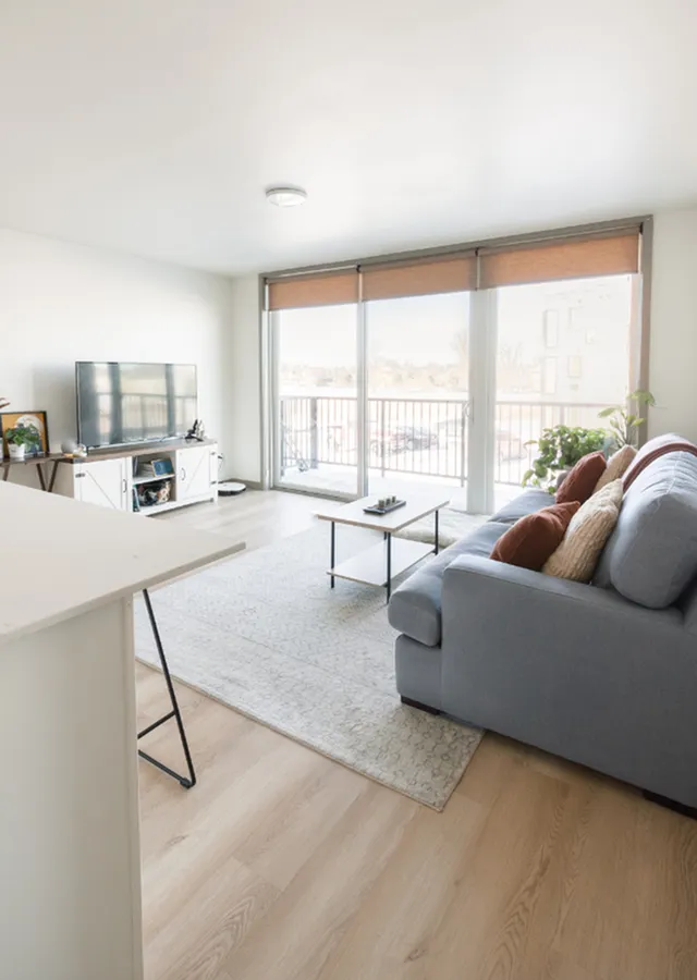 Bright and modern living room with a comfy gray sofa, sleek coffee table, and large windows offering a stunning balcony view.