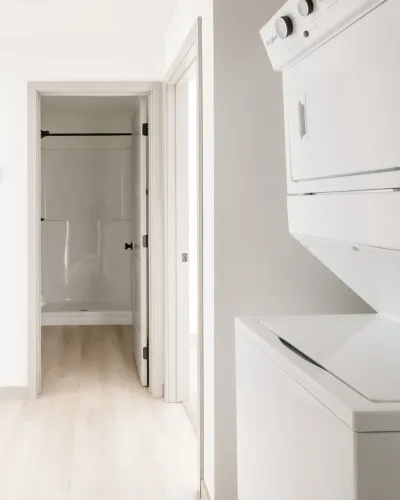 Bright apartment featuring in-unit washer and dryer with a sleek bathroom view, showcasing modern amenities and clean design.
