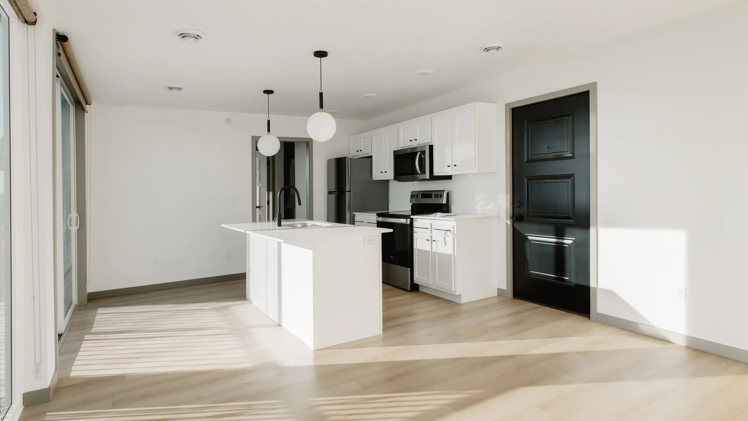 Sleek modern kitchen with bright open layout, featuring an island, stainless steel appliances, and elegant white cabinets.