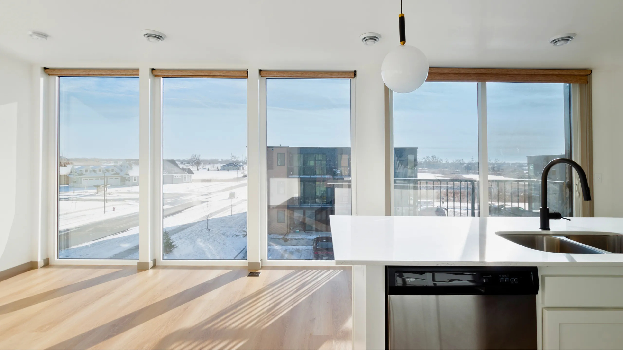 Bright kitchen area with modern sink and elegant lighting, featuring expansive floor-to-ceiling windows showcasing stunning snowy views.