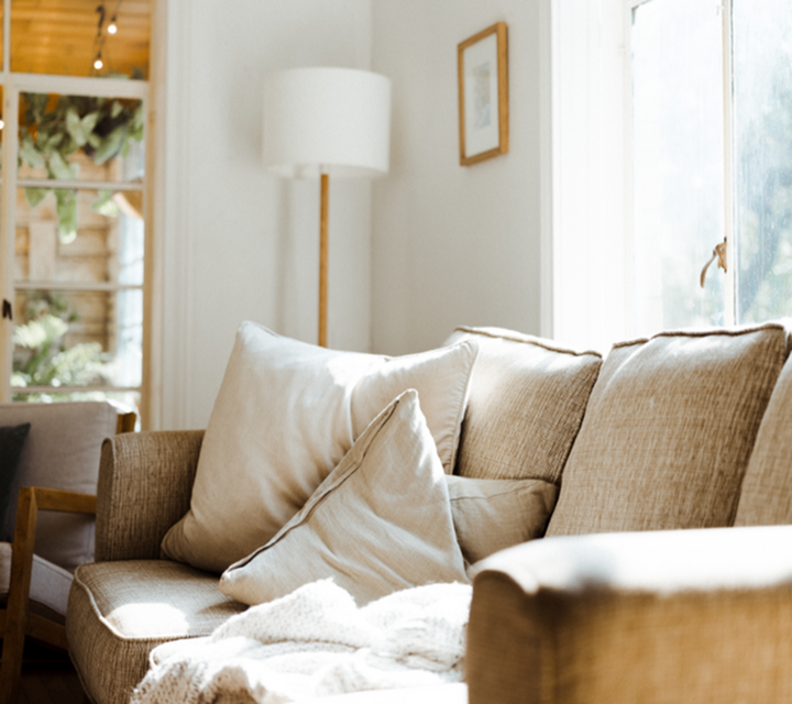 Inviting living room with a cozy beige sofa and soft pillows bathed in natural light, perfect for relaxation.