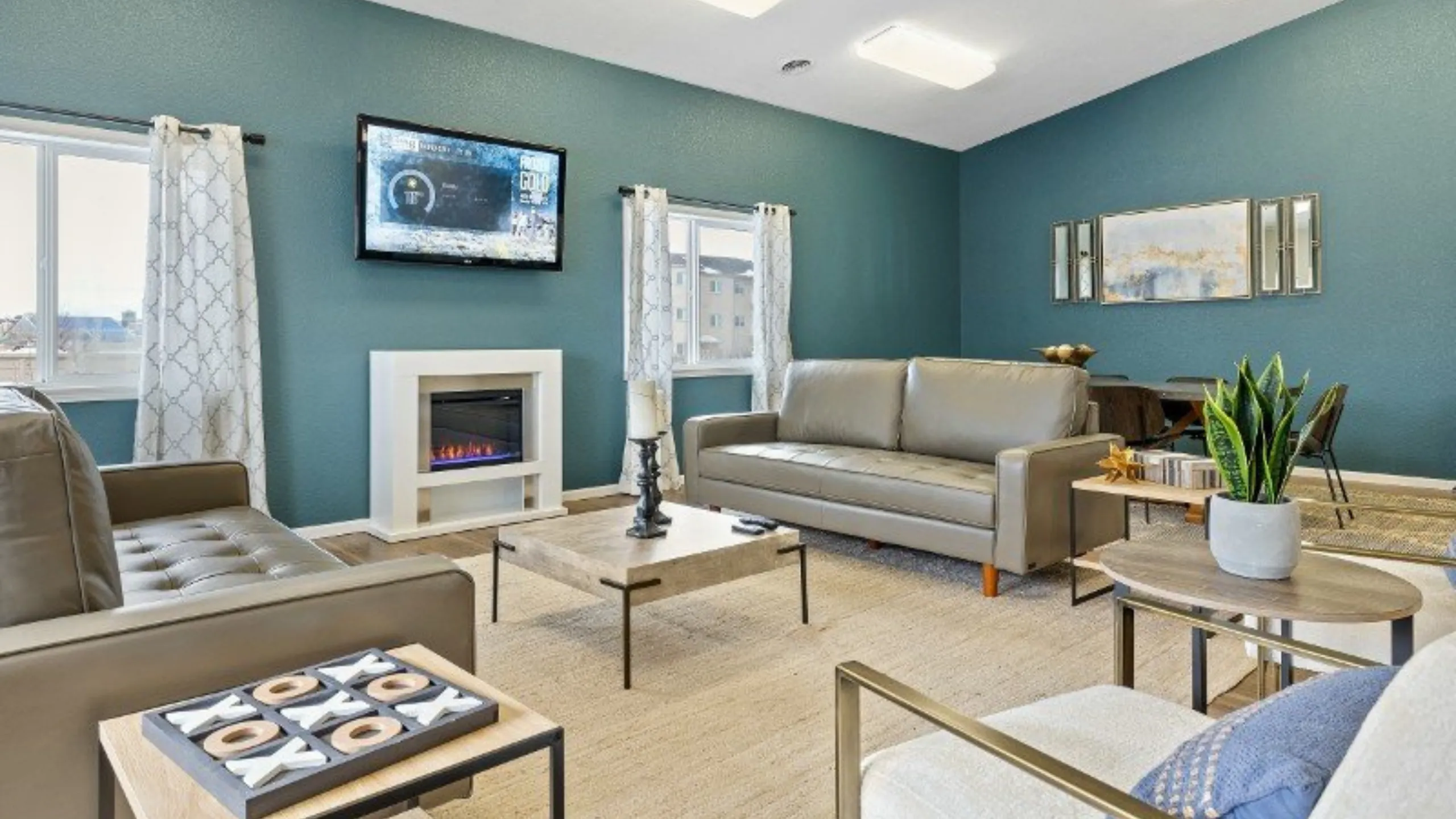 Chic living room with modern decor, featuring plush sofas, a cozy fireplace, and elegant artwork on teal walls.