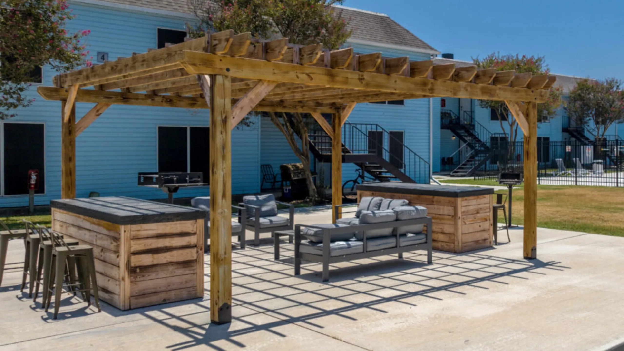 Charming outdoor pergola with modern seating and sleek bar stools, perfect for relaxation and entertainment.