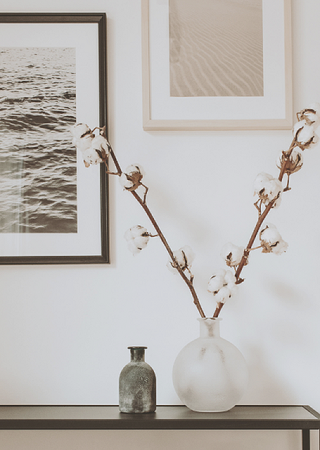 Minimalistic decor featuring a chic console table with elegant vases and framed art on a serene white wall.