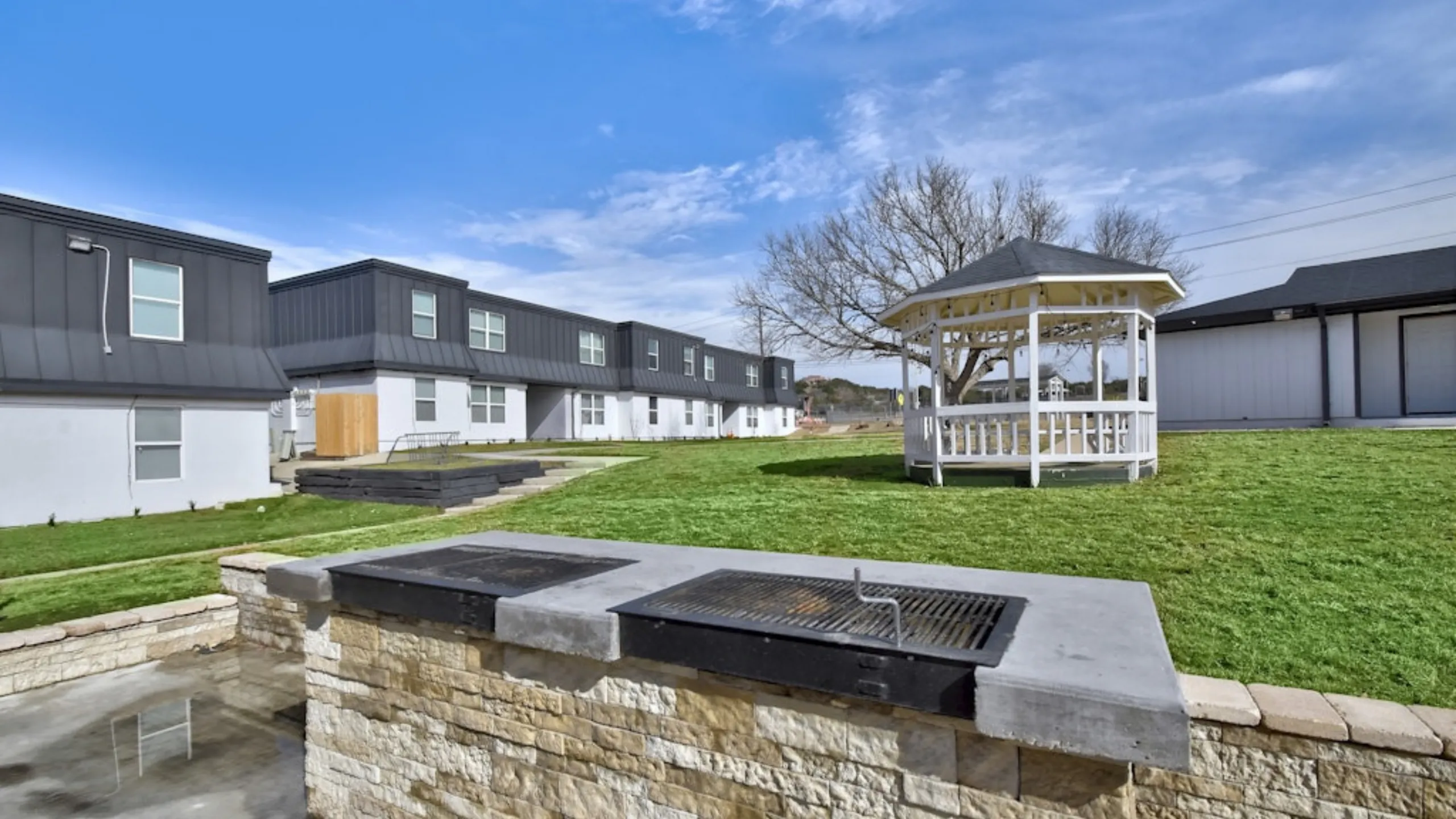 Charming outdoor space with well-maintained lawn, gazebo, and built-in barbecue area, perfect for relaxing and entertaining.