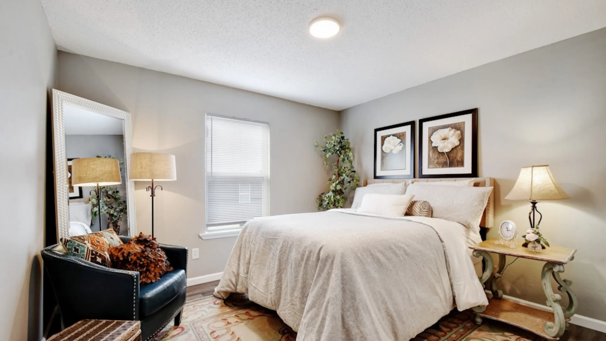 Inviting bedroom featuring a cozy bed, stylish decor, elegant floor lamp, and natural light through a window.