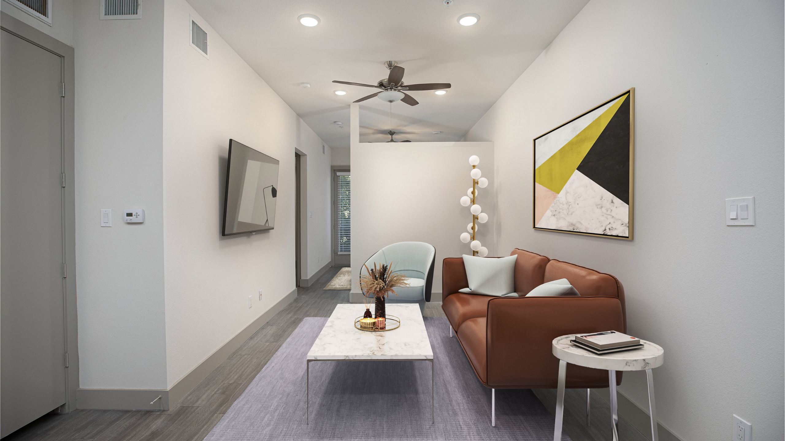 Modern apartment living room with stylish decor, featuring a sleek brown leather sofa, contemporary art, and a chic marble coffee table under warm recessed lighting.
