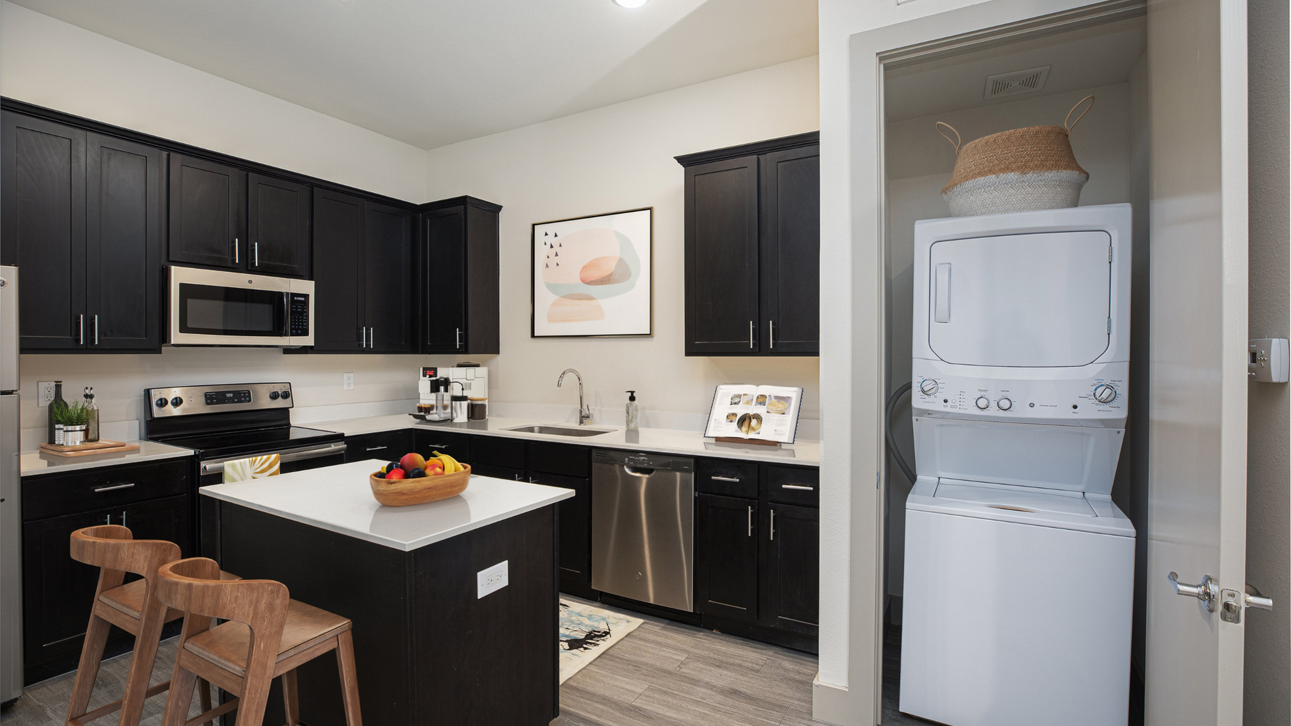 Modern kitchen with sleek dark cabinets, stainless steel appliances, and a convenient in-unit washer and dryer.