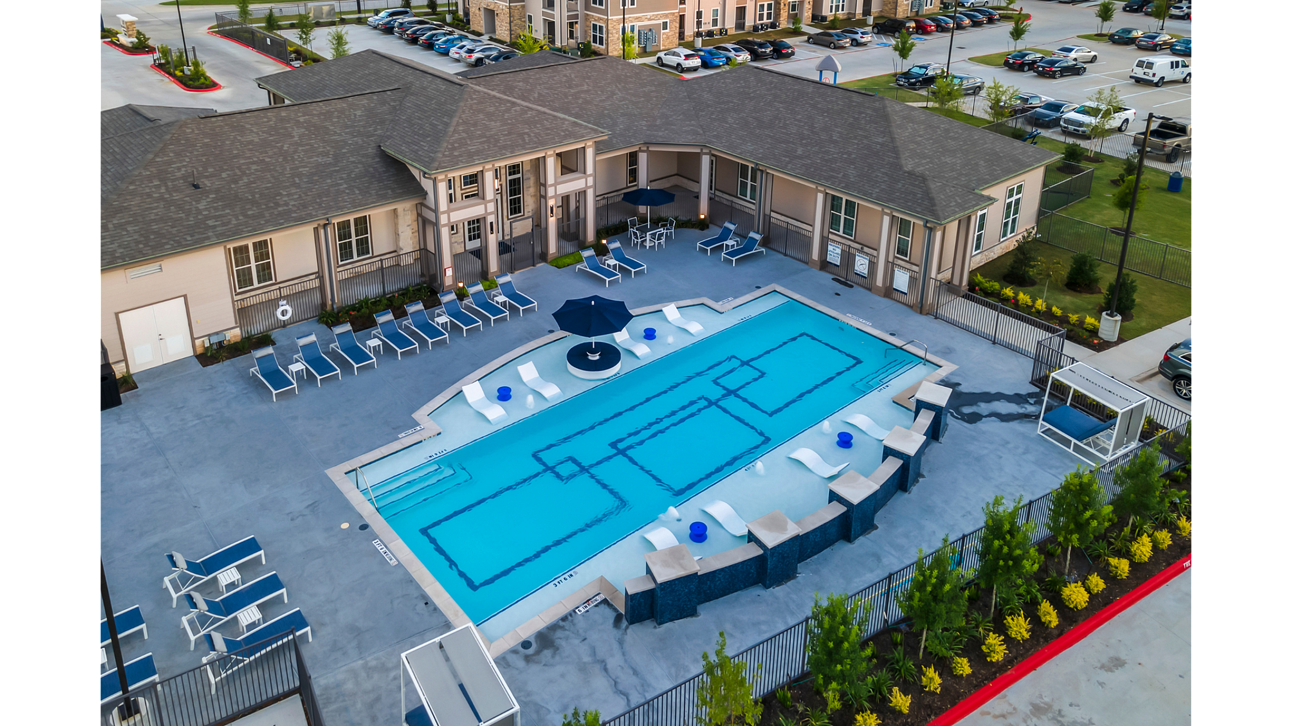 Elegant apartment complex with a resort-style swimming pool, surrounded by stylish lounge chairs and vibrant landscaping.