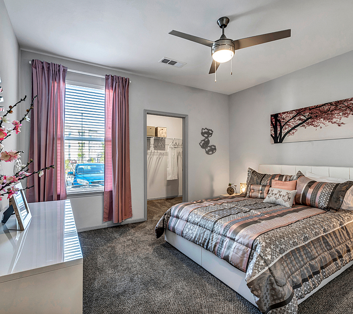 Inviting bedroom with modern decor, featuring a plush bed with patterned bedding, stylish wall art, and a large window with elegant pink curtains.