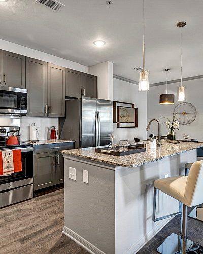Modern kitchen with sleek cabinets, granite countertops, and a spacious island with bar seating, offering a stylish and functional living space.