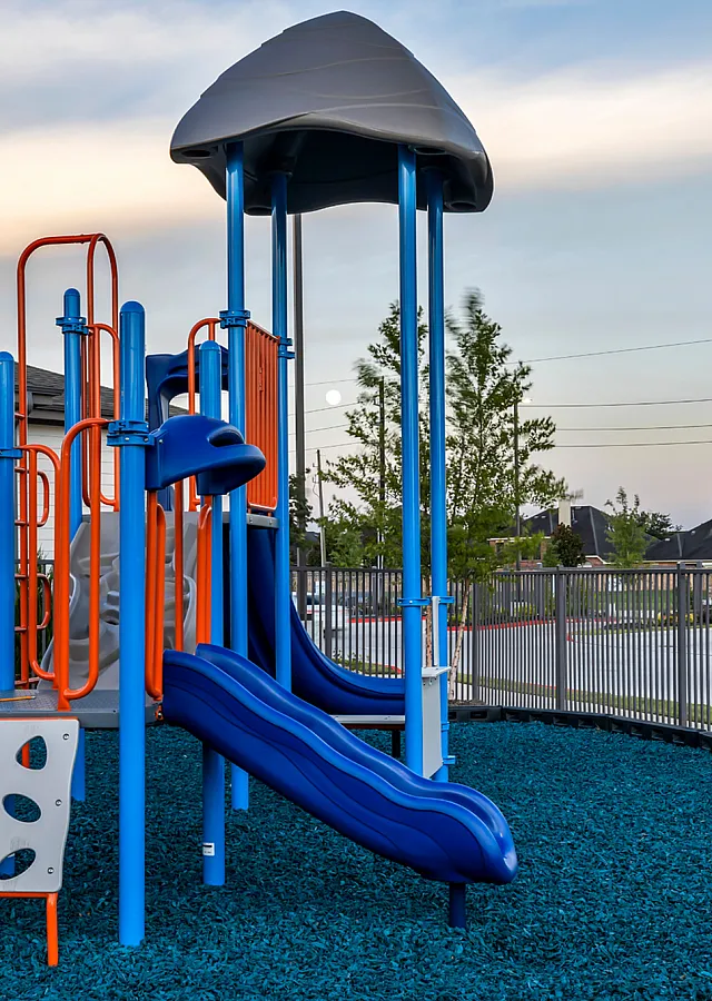 Inviting playground with a vibrant blue slide, colorful climbing structure, and safe, enclosed area perfect for family enjoyment.