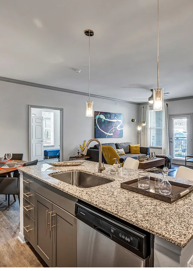 Modern open-concept apartment showcasing a chic kitchen with granite countertops, stylish dining area, and a cozy living room with contemporary decor.