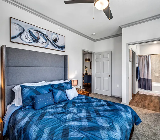 Inviting bedroom featuring a plush blue bedspread, modern artwork, and en-suite bathroom for ultimate comfort and style.