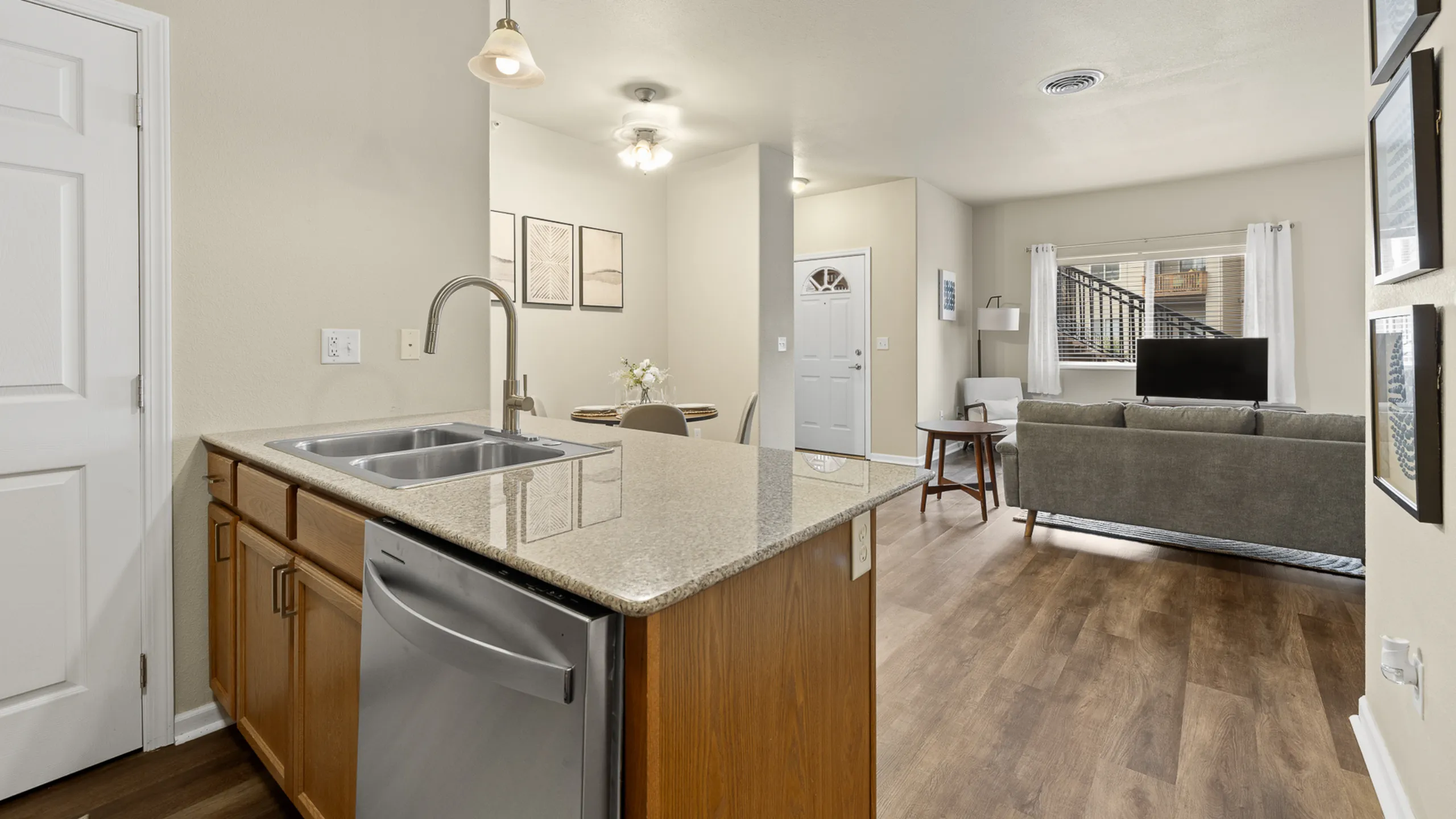 Modern open-plan living space featuring a sleek kitchen with granite countertops, cozy dining area, and inviting living room with stylish decor.
