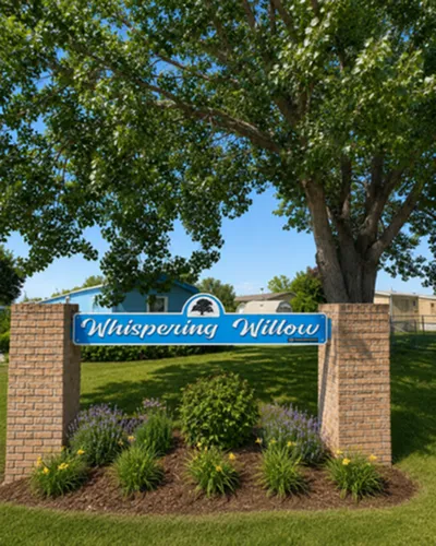 Charming entrance sign for Whispering Willow community surrounded by lush greenery and vibrant landscaping.