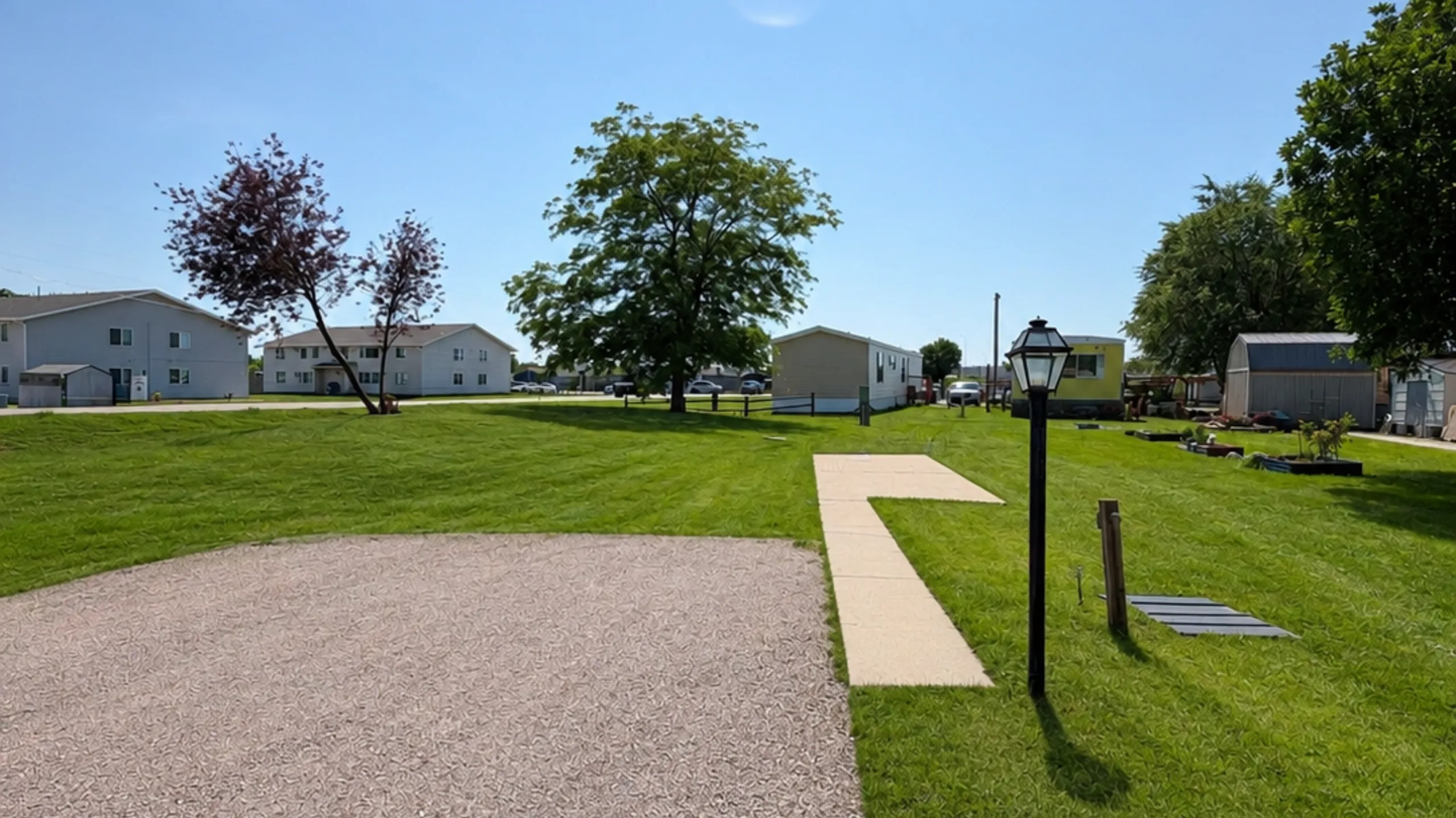 Charming residential area featuring lush green lawns, trees, and cozy homes under a clear blue sky, perfect for tranquil living.
