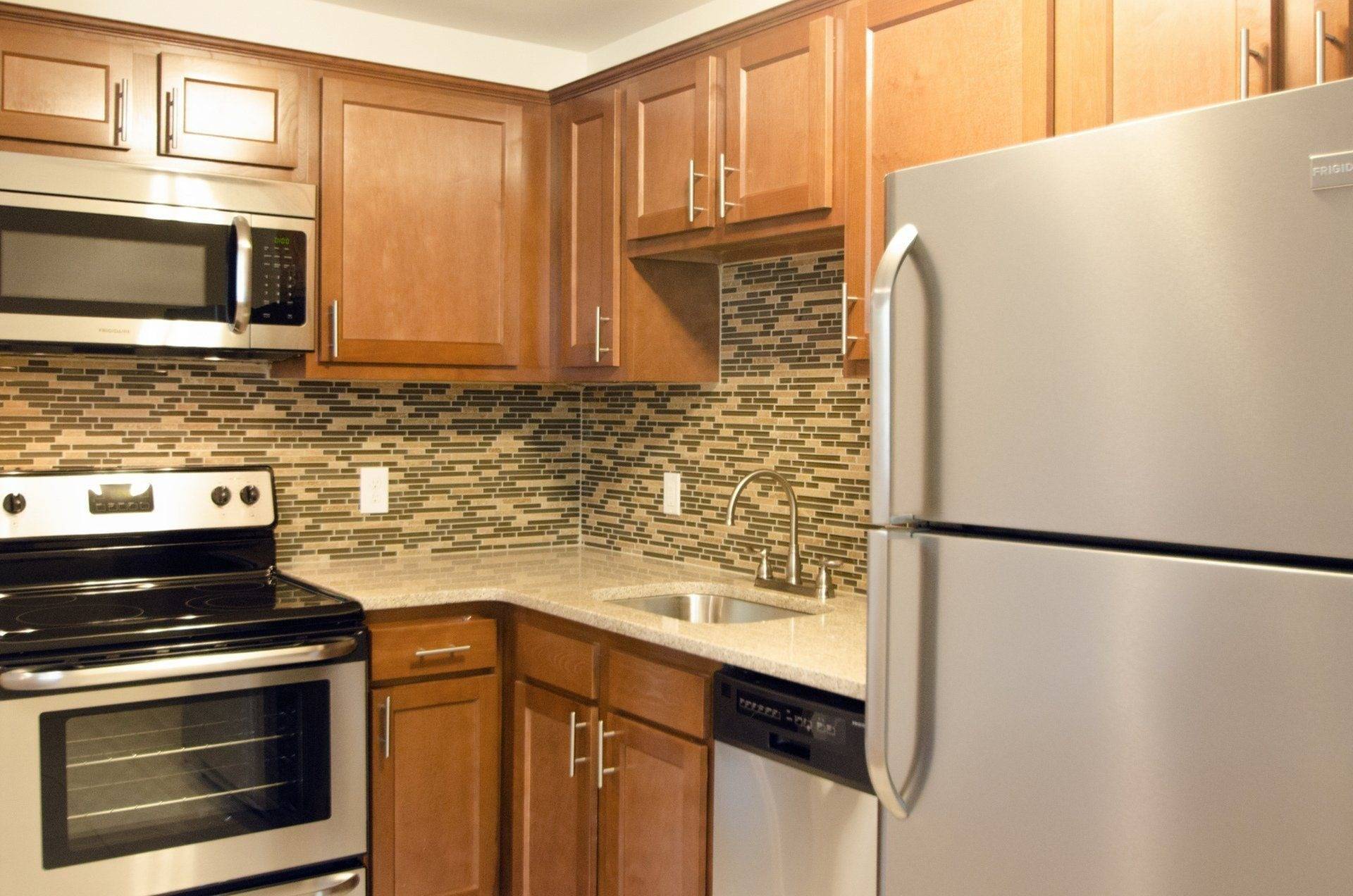 Apartments in West Chester, PA - Audubon Pointe - Kitchen With Stainless Steel Appliances, Light Wood Cabinetry, Granite-Style Countertops, and Tile Backsplash