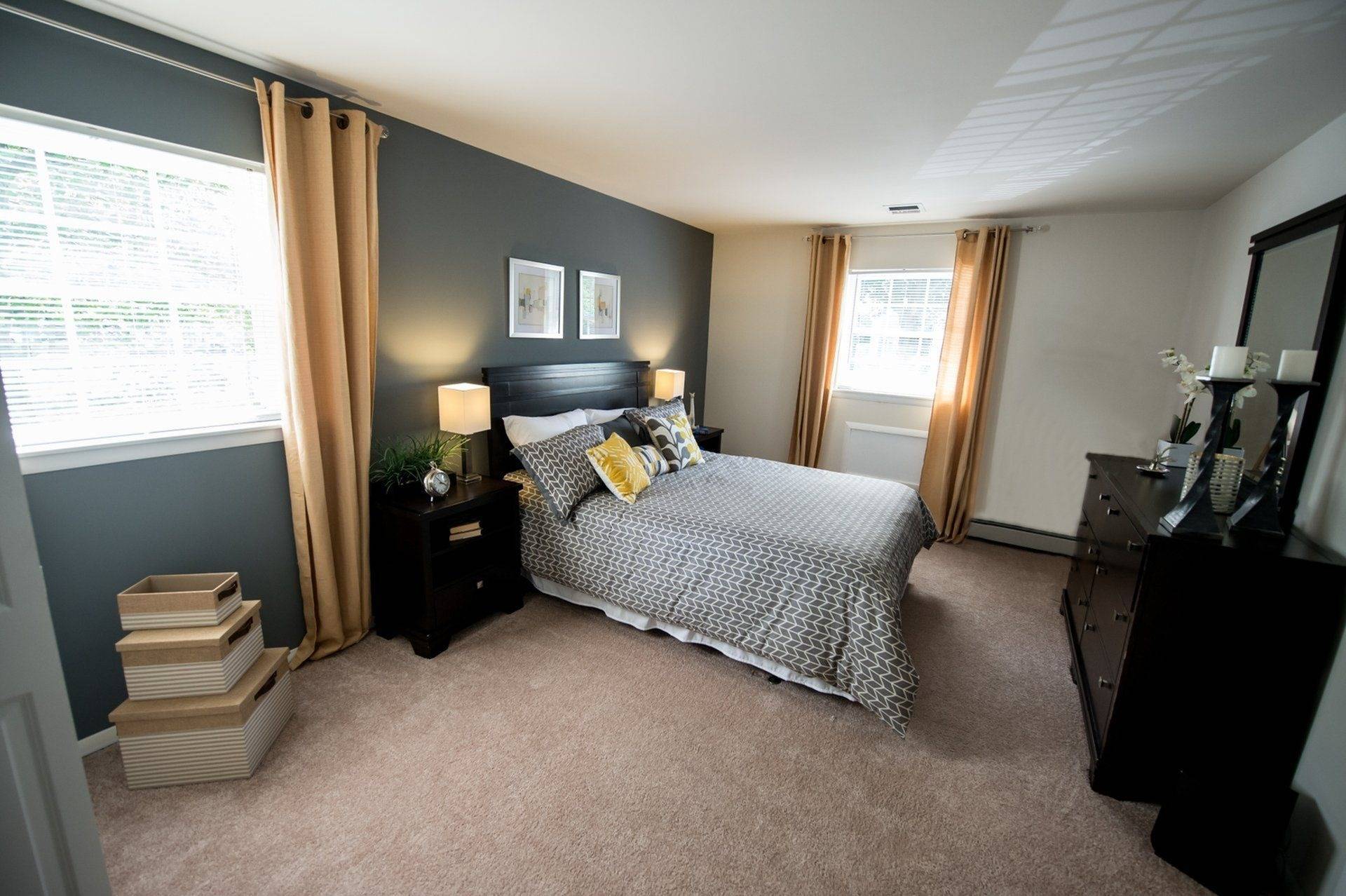West Chester Apartments - Spacious Bedroom With Carpet Flooring, Modern Decor, And Two Windows With Blinds.