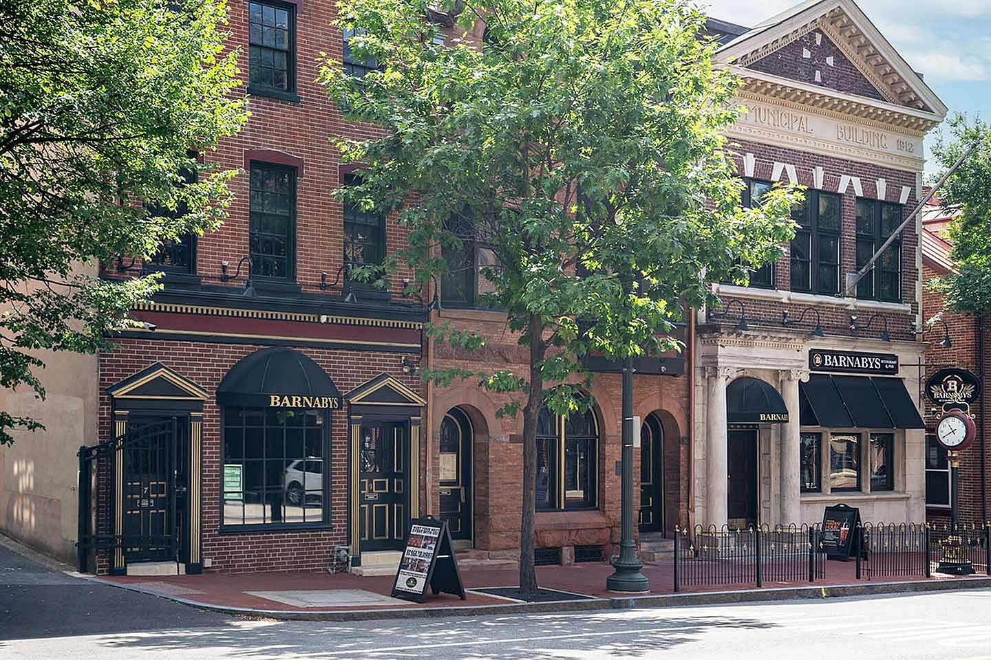 Charming brick buildings with classic architectural details and lush greenery on a lively street.
