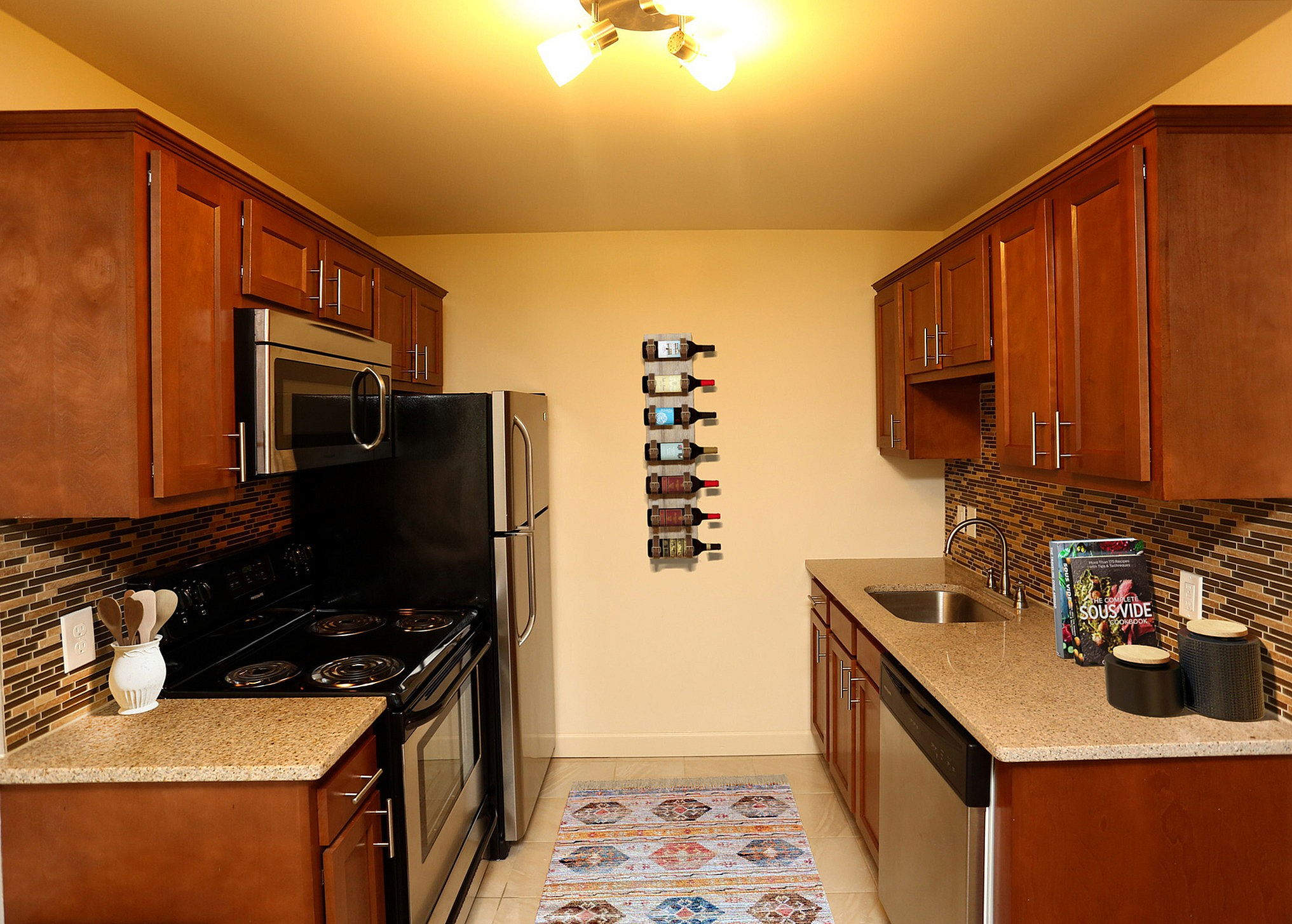 Modern kitchen with stainless steel appliances, elegant wooden cabinetry, and a vibrant backsplash, complemented by a chic wine rack display.