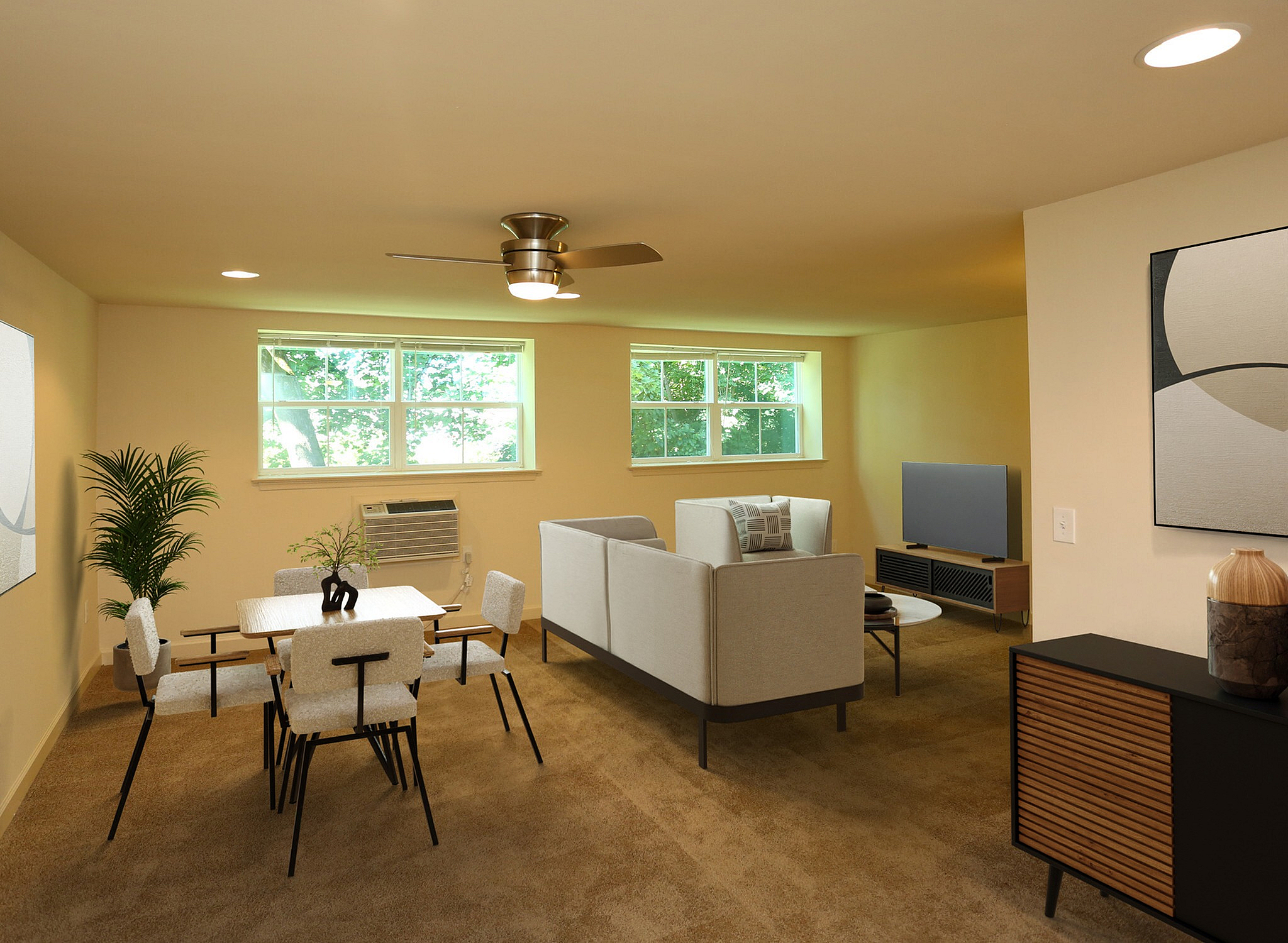 Bright and welcoming living area with modern furniture, an elegant dining set, and large windows overlooking lush greenery.