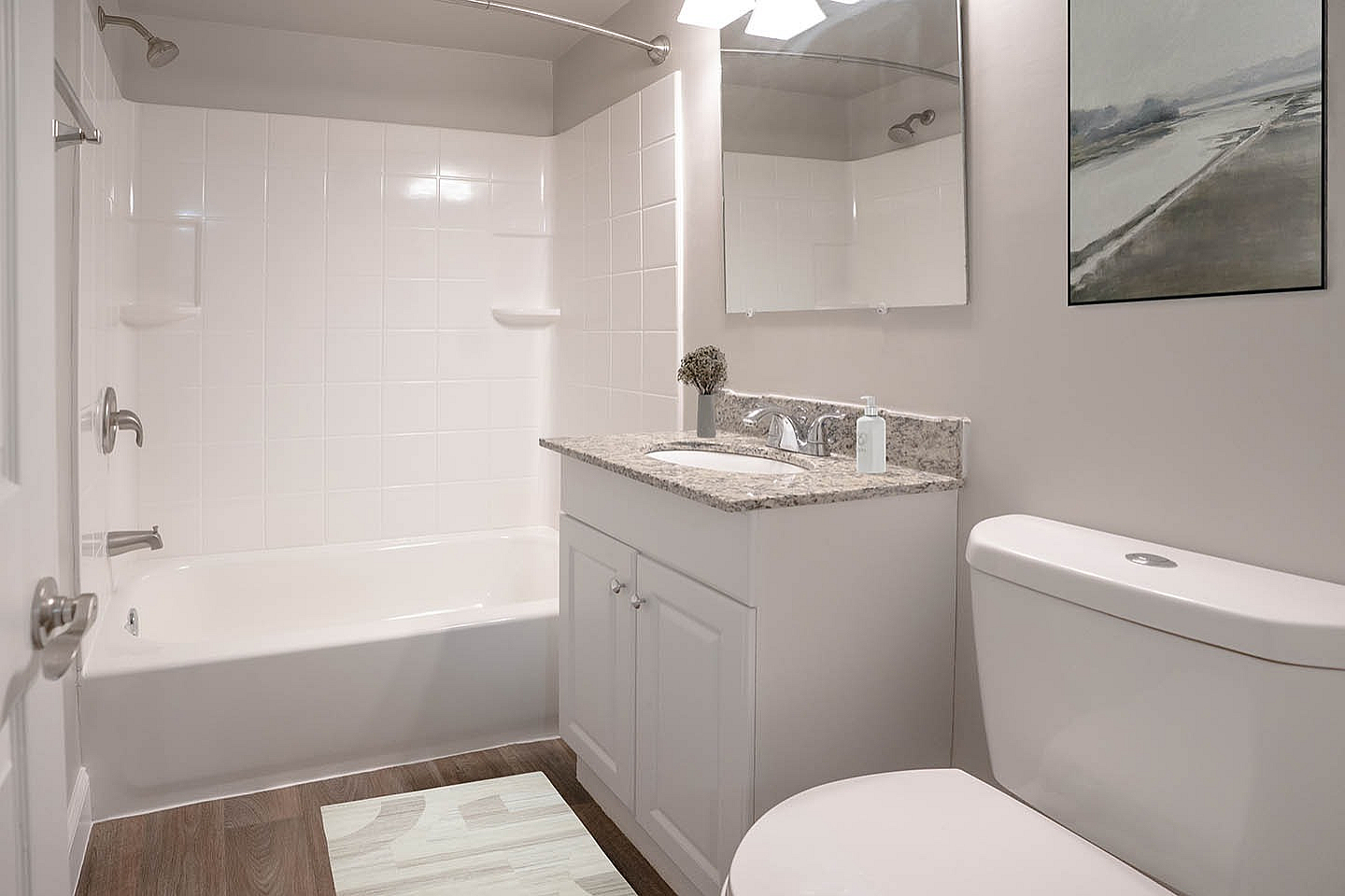 Elegant bathroom with modern fixtures, featuring a spacious bathtub, sleek vanity with granite countertop, and stylish wall art.