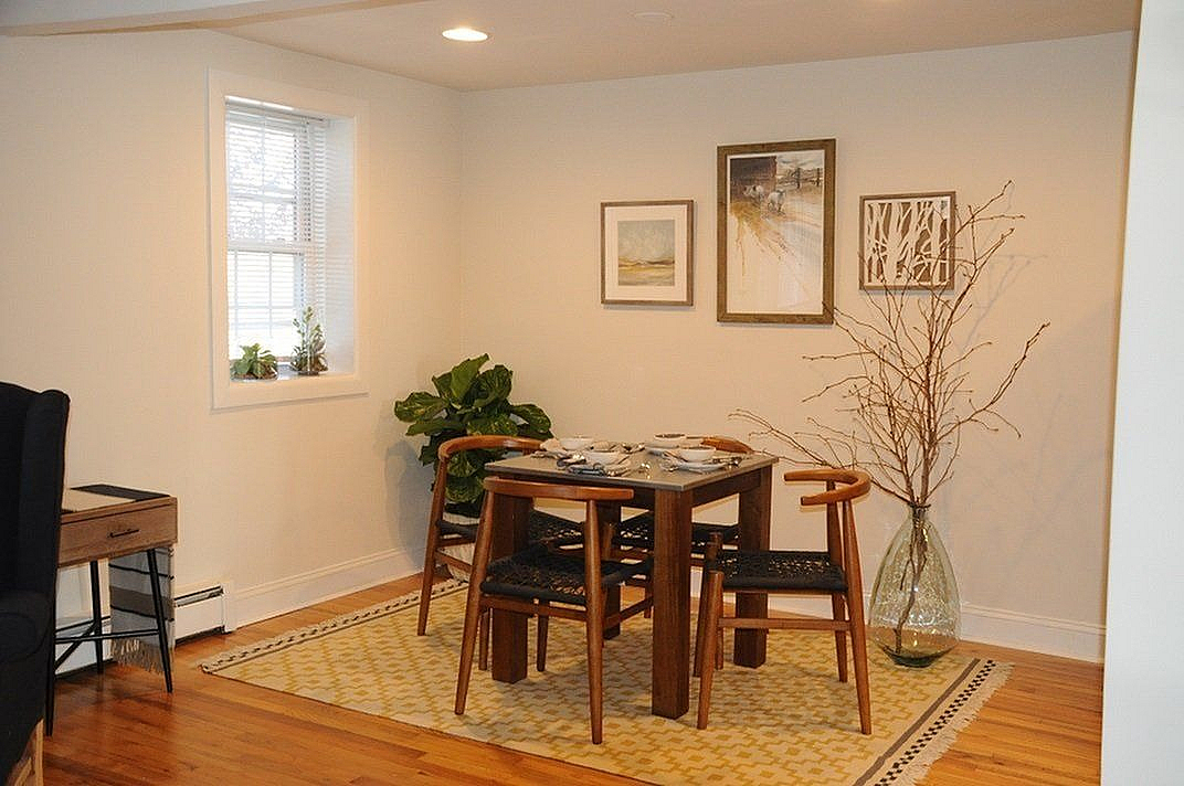 Charming dining nook with modern wood furniture, accented by stylish wall art and vibrant greenery.