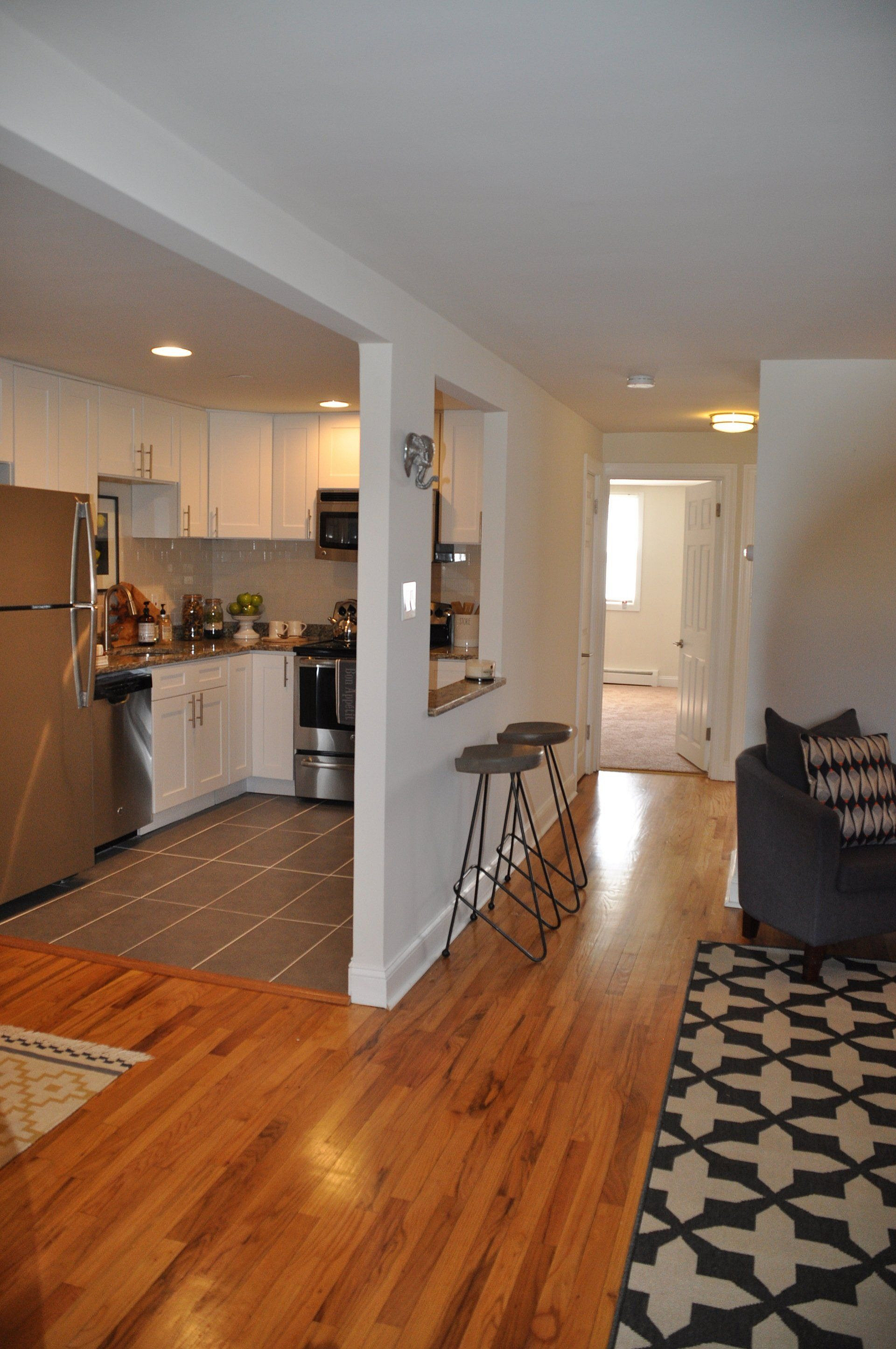 Chic open-concept kitchen with modern stainless steel appliances, elegant barstools, and a cozy living area.