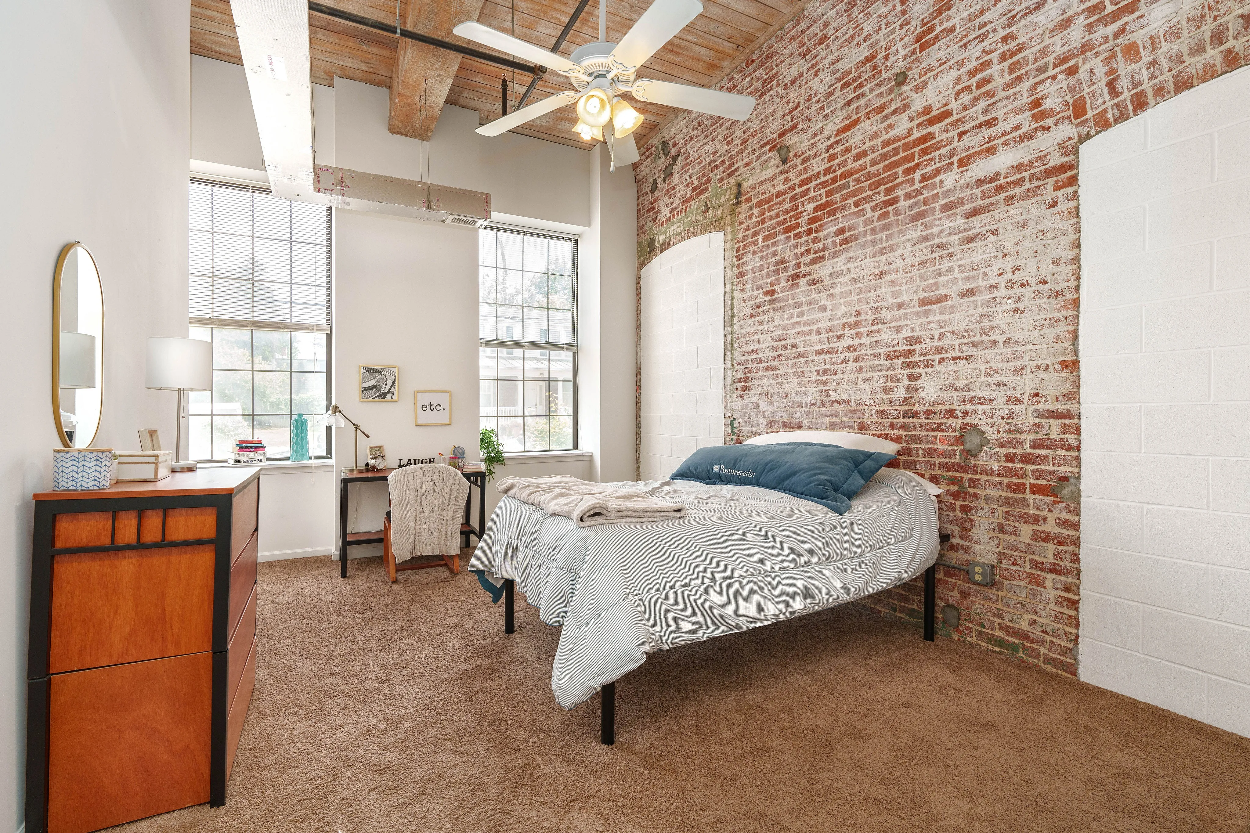 Chic loft bedroom featuring exposed brick walls, natural light, and modern decor for a cozy urban retreat.