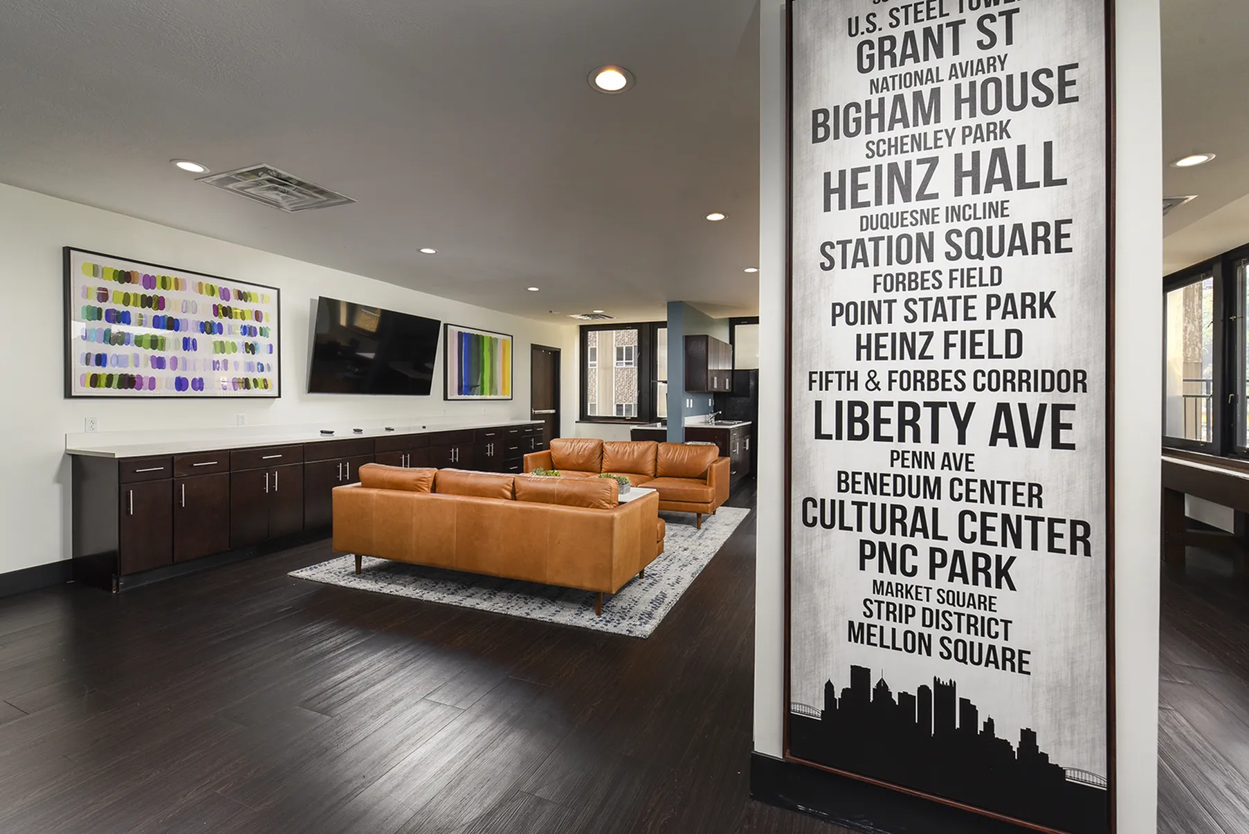 Modern lounge area with stylish leather sofas, vibrant artwork, and sleek cabinetry, enhanced by a chic urban-themed mural.