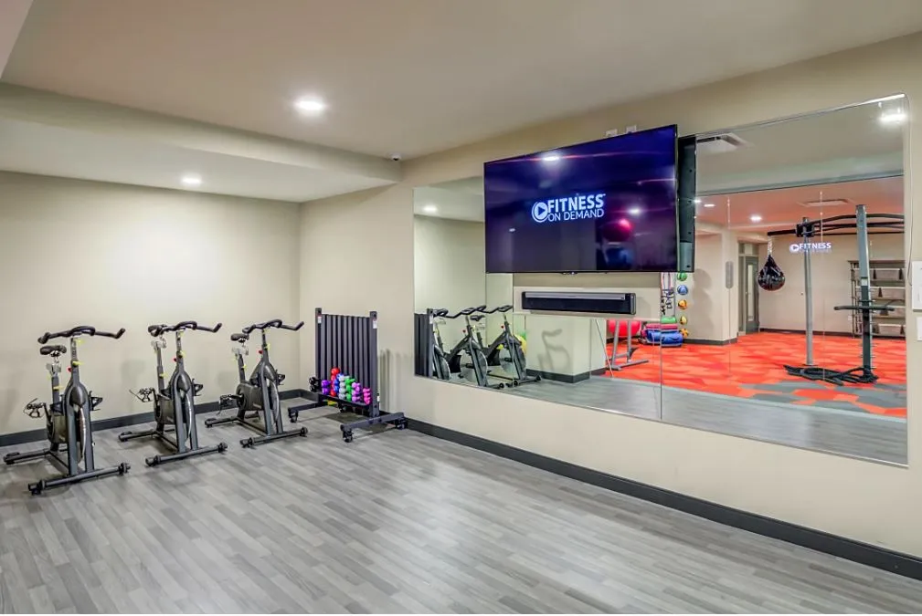 Chic fitness room featuring state-of-the-art exercise bikes, mirrored wall, and digital workout screen.