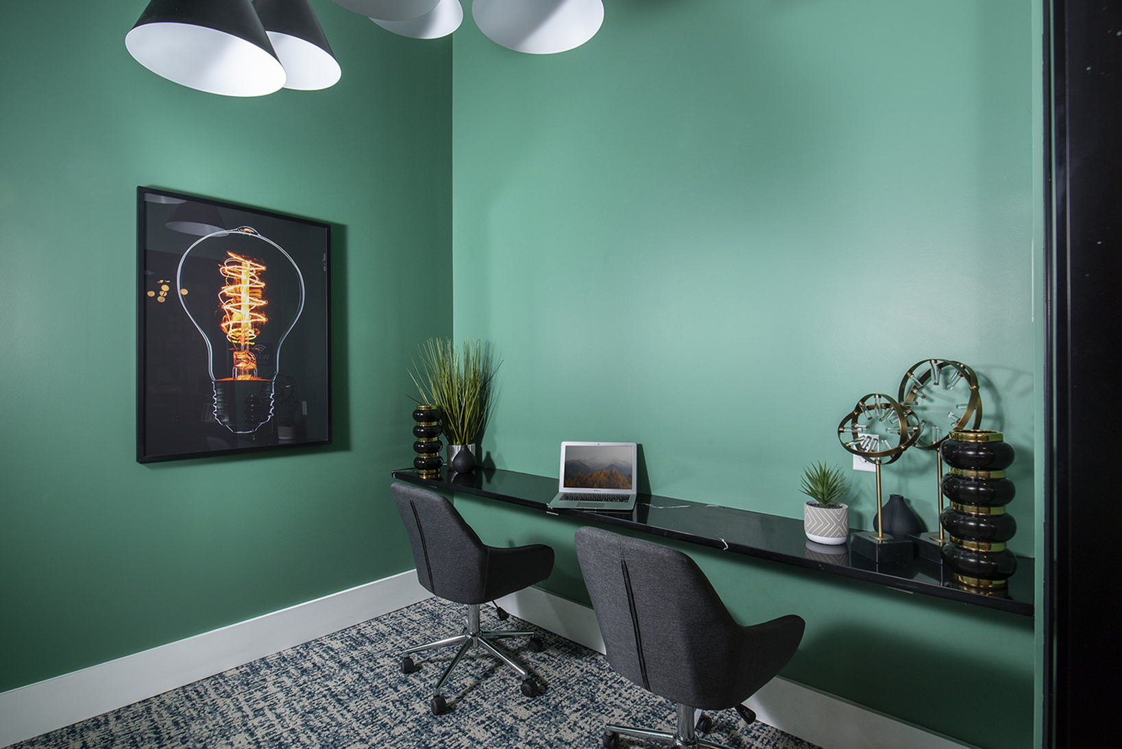 Chic green home office with modern decor, featuring a dual desk workspace and stylish gray chairs.
