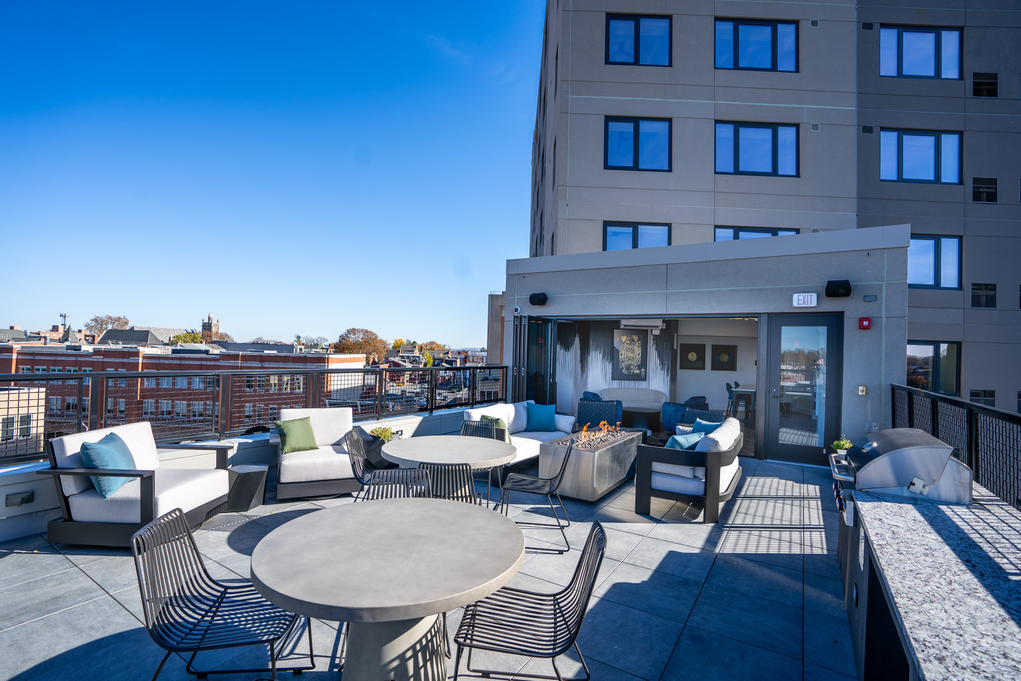 Chic rooftop lounge with cozy seating, modern fire pit, and stunning city views.