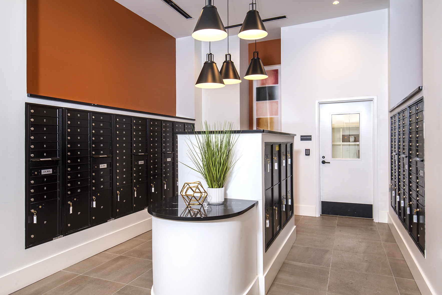 Modern mailroom with sleek black mailboxes, sophisticated pendant lighting, and contemporary decor for a luxurious apartment experience.