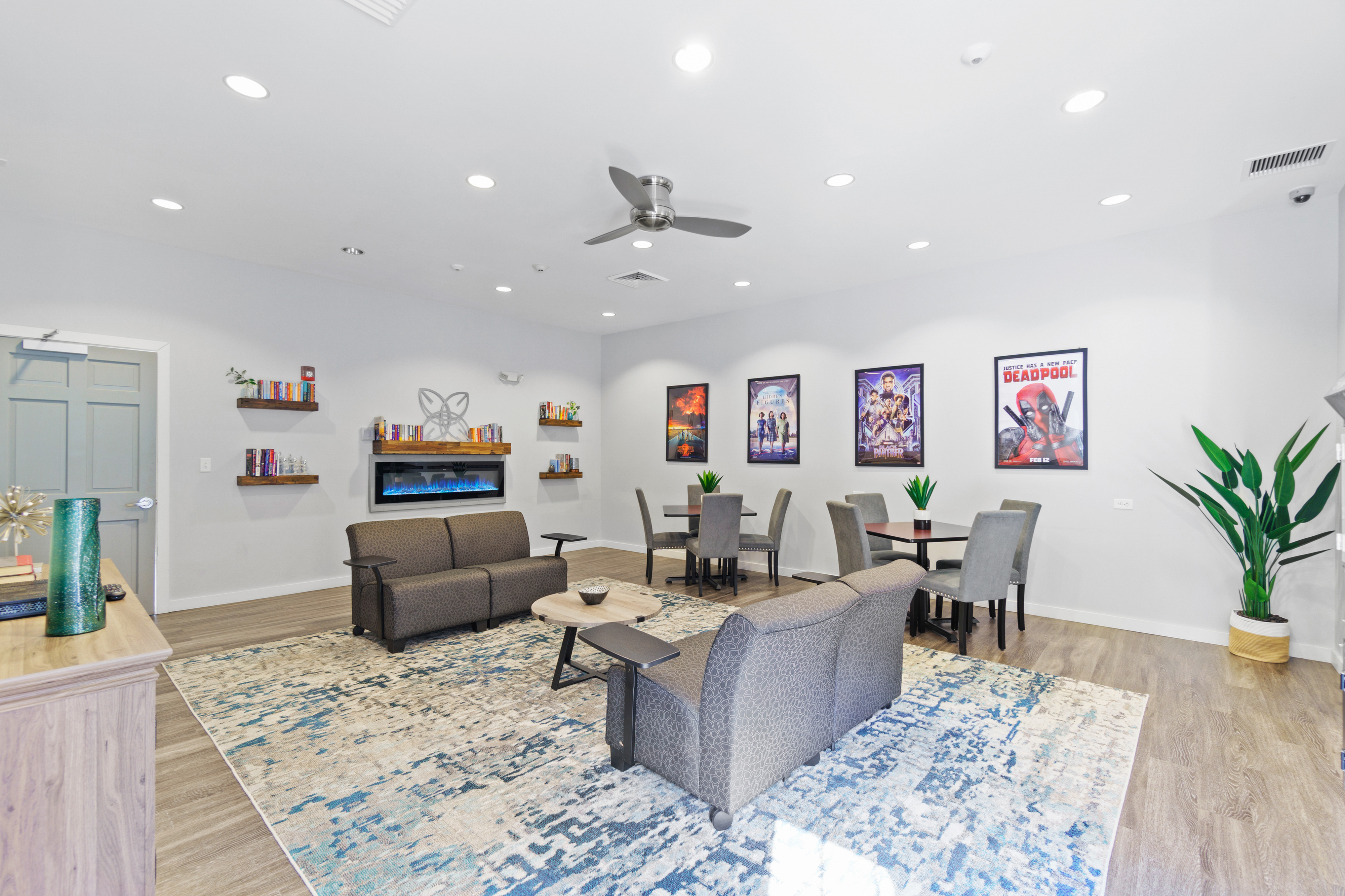 Chic communal lounge area featuring modern seating, vibrant artwork, a decorative fireplace, and stylish shelving in a welcoming open space.