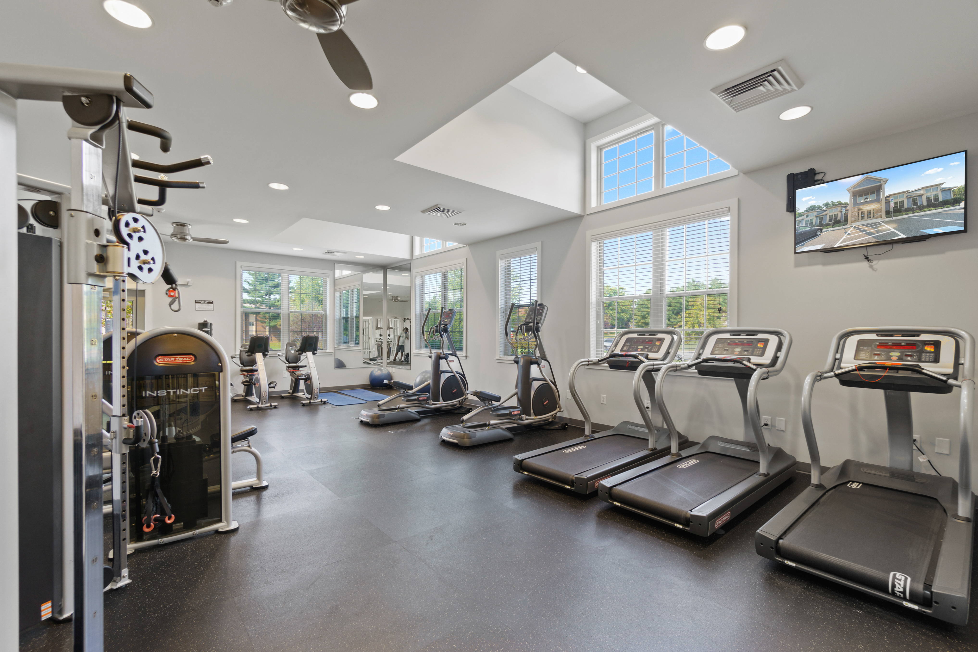 Modern fitness center with state-of-the-art equipment, including treadmills and strength machines, under ample natural light.