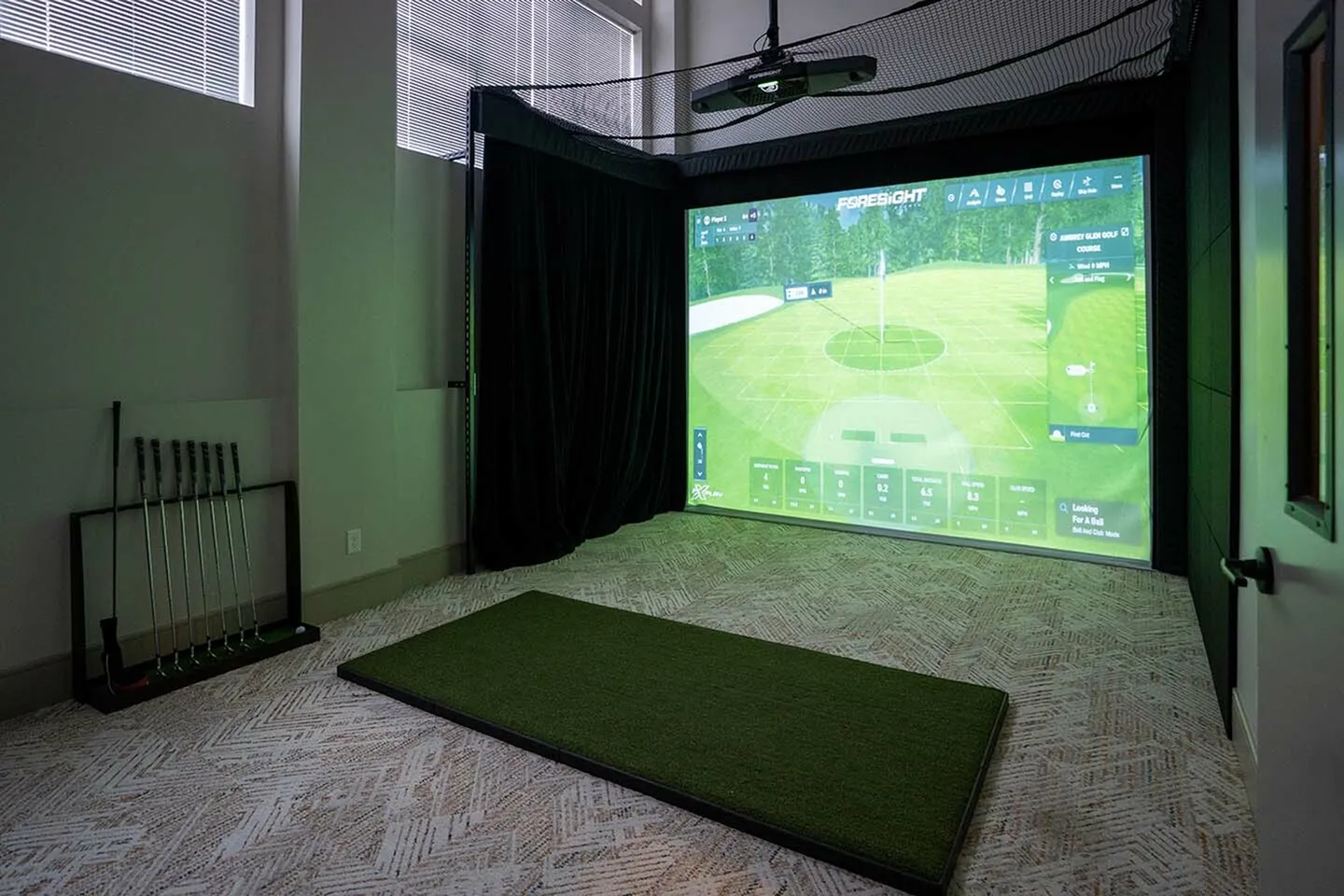 Luxurious indoor golf simulator room featuring high-tech equipment, sleek design, and natural light filtering through large windows.