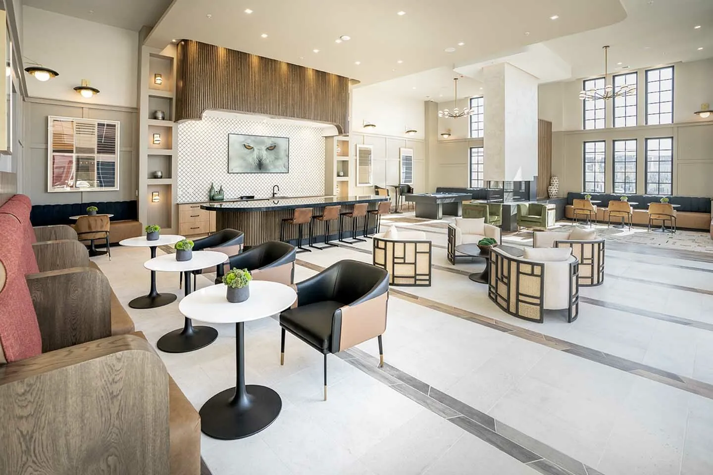 Elegant and spacious common area with modern decor, featuring cozy seating arrangements, a stylish bar area, and large windows for natural light infusion.