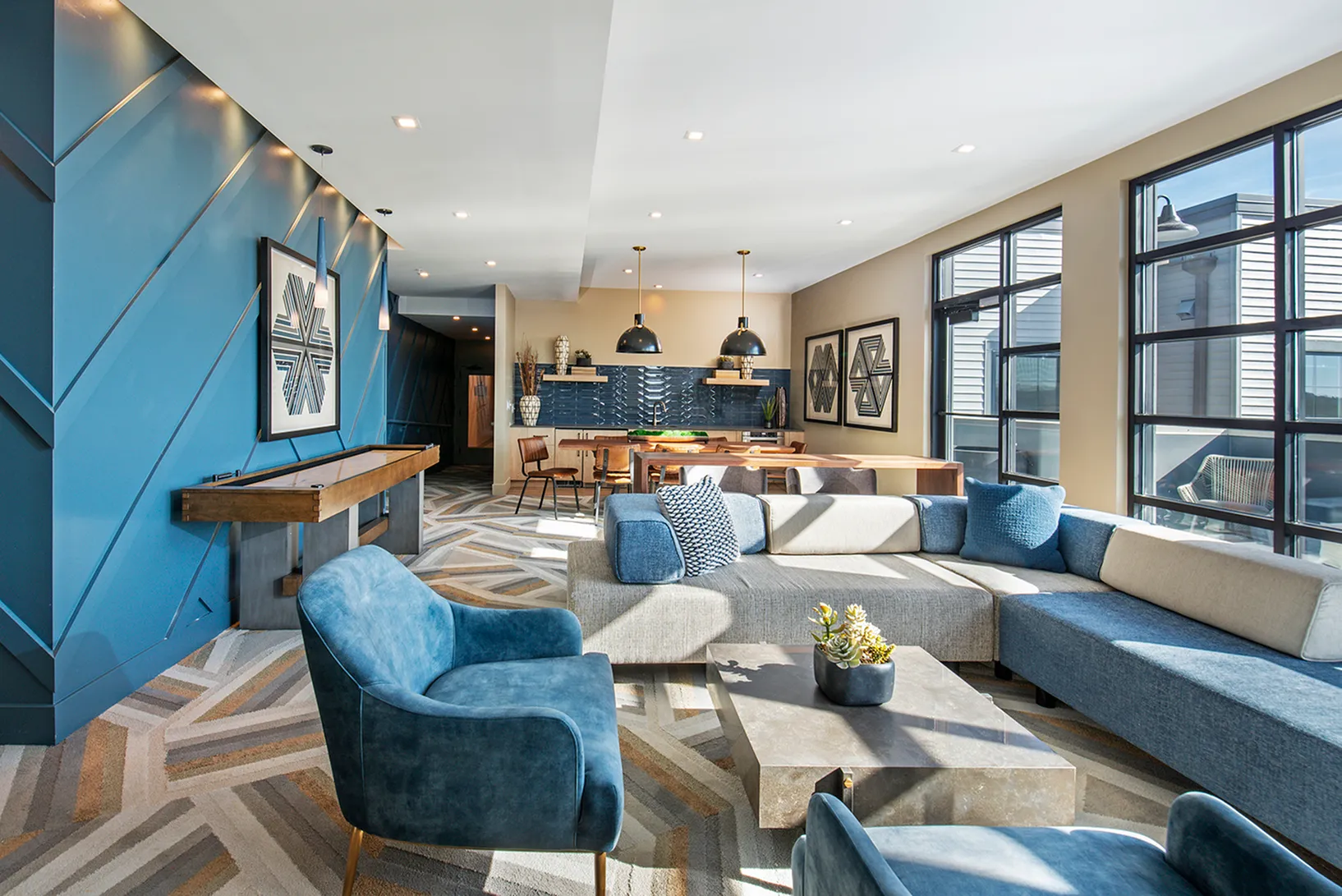 Chic open-concept living space with modern blue accents, abundant natural light, and stylish furniture.